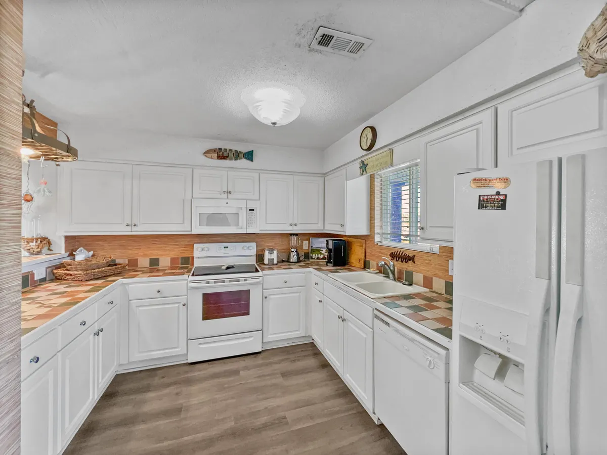 A bright kitchen with a central island, stove, sink, and a window letting in natural light, designed for meal preparation and social gatherings. The layout promotes conversation and is equipped with modern appliances and ample counter space.