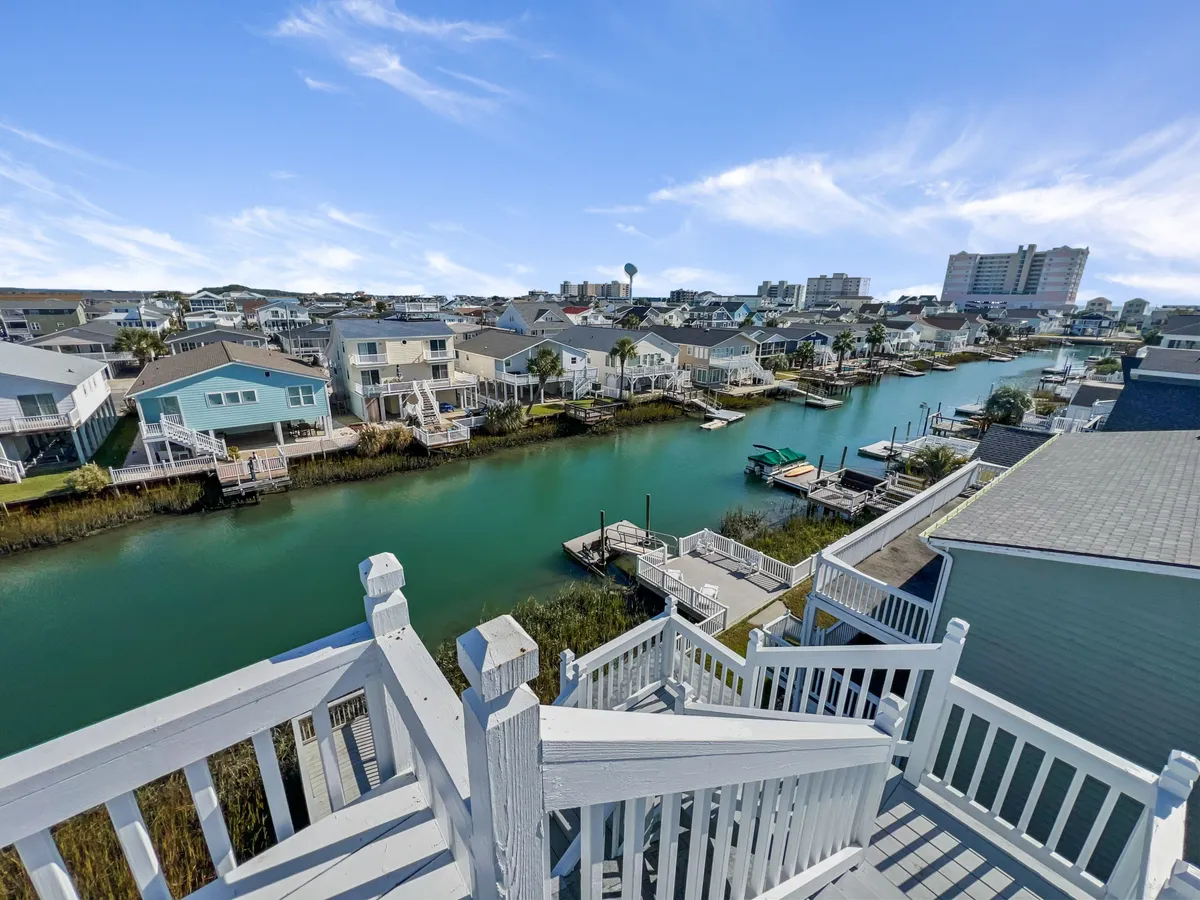 This image showcases a tranquil canal with neighboring houses and boats, as well as a staircase leading down to the water. The deck appears inviting, with scenic views ideal for relaxing after outdoor adventures. The atmosphere is peaceful, highlighting the unique waterfront setting of the property.